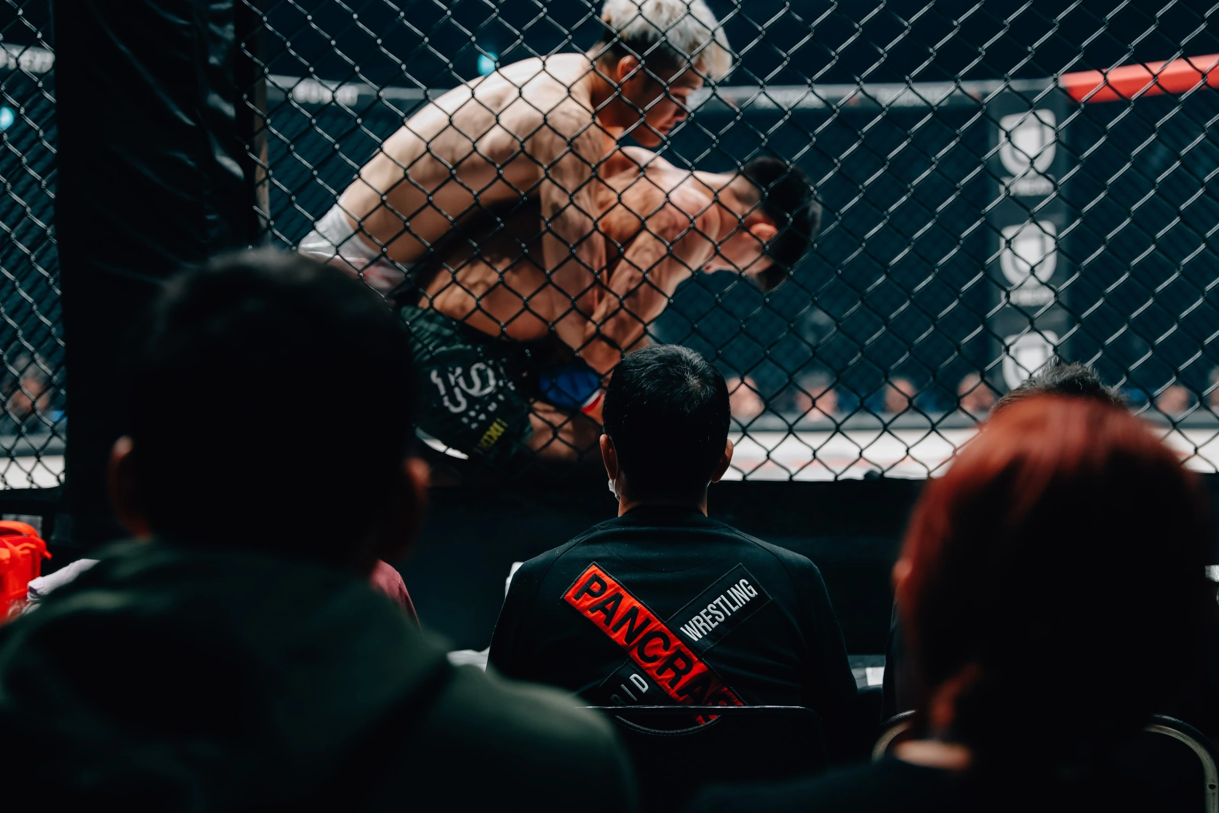 Spectators watching a PANCRASE bout through the cage